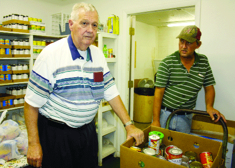 Volunteers Bill Law and Paul Ratliff stock the shelves in the food pantry Wednesday.