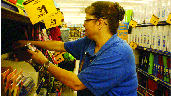 Stephanie Bolden, a cashier at the Andalusia Fred’s Store, finishes straightening the school supply aisle Monday.                                 Stephanie Nelson/Star-News