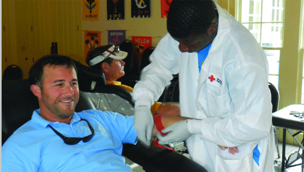 Patrick Stokes wraps blood donor David Carter’s arm after Carter gave a pint a blood at the Red Cross Blood Drive hosted by St. Mary’s yesterday. Chet Thrash, shown in the background, also was among the 23 people who gave blood, topping the drive’s goal of 20 units.    