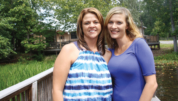 Misty Lanier and Selena Hammett stand on the pier behind their new venture, Rivers Seven.