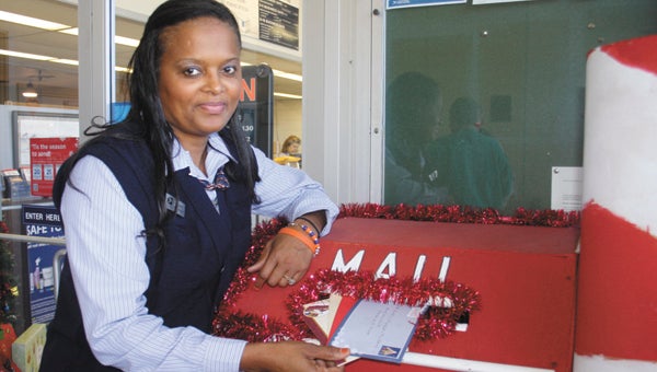 Melisha Heard watches for new visitors at the Andalusia Post Office, while dropping a few new letters to Santa in the mailbox designated for the North Pole.