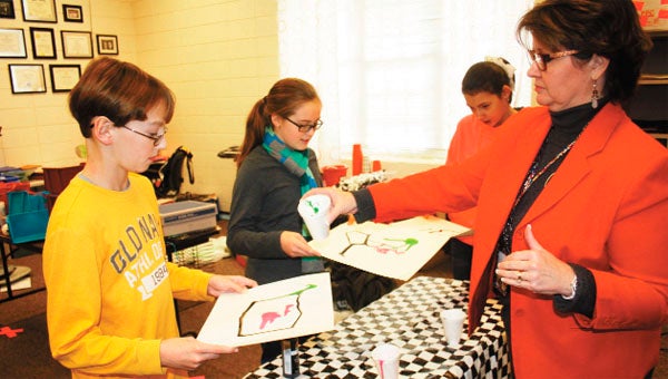 Cathy Powell helps students, from left, Dalton Spears, Rachel Fleming and Sydney Ray with a project.