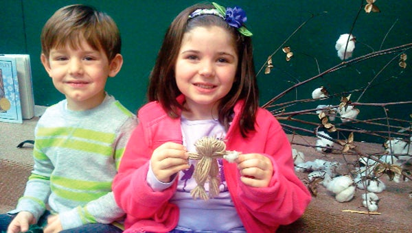 Madison Norris and Tate Watson with cotton plants and string dolls.