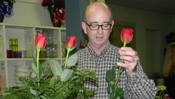 Alan Cotton arranges red roses, a staple for Valentine’s Day