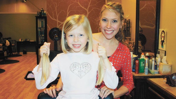 Sara Catherine Sansom shows off the nine inches of hair she donated to children fighting cancer while posing with her mom, Ashton Sansom.