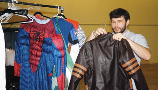 Blake Hostetter prepares to become Marvel character Wolverine, choosing the well-known jacket from a rack of hero costumes.