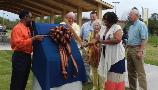 Sheila Smith cuts the ribbon on the marker at the pavilion dedicated in her husband’s memory on Saturday. She is shown with council members Will Sconiers, Kennith Mount, Hazel Griffin, Ralph Wells and Rep. Mike Jones. 