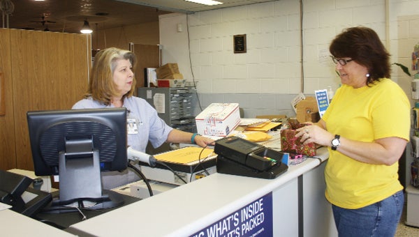 Postal worker Susan Brown assists Tara Cook Monday afternoon at the Andalusia Post Office. 
