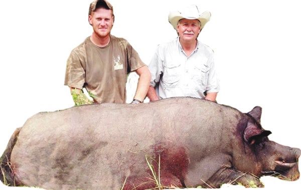 Nathan Shirey is shown with property owner Terry Moody with the more than 400-pound feral hog that he and friends killed near Luverne this weekend. 