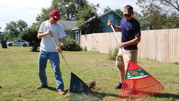 Clients Rex White (left) and Alex Bass rake grass clippings.