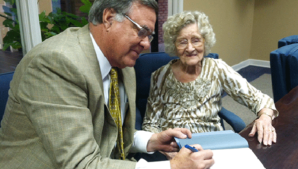 Flowers signs a copy of his book for Margaret Eiland, who is about to celebrate her 98th birthday. Mrs. Eiland said she enjoys reading his column each week. 