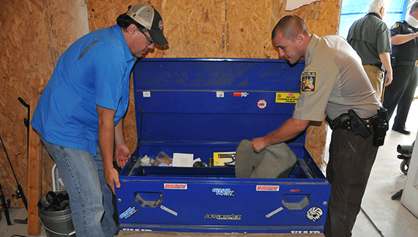 Dave Harrell and a CCSO deputy look through evidence at a drug bust in July. 