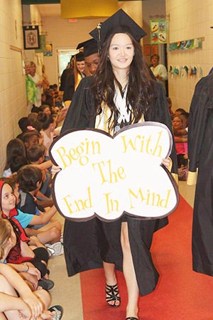 OHS valedictorian Kayla Baker leads the group with a sign that says “Begin with the end in mind.” 