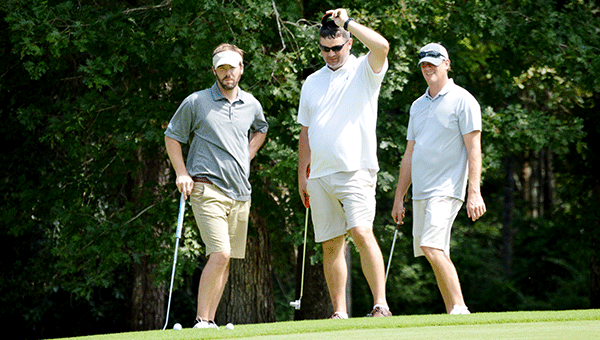 Horn Beverage Company’s team of Kyle Bryan, Brandon Hill and Forrest Hancock discuss strategy as their ball sits just off the edge of the green. Josh Dutton/Star-News
