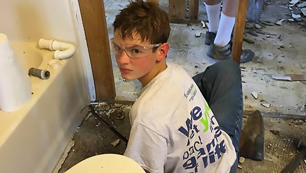 Caleb Blackston helps rip up flooring in a flooded home. Courtesy photo