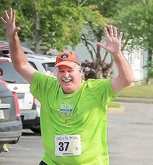 Cotton holds up both hands near the end of his 10th 5K. 