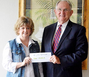 Dr. Jim Krudop accepts a contribution from Andalusia Health Services member Cathy Alexander on behalf of Camp ASCCA. Dr. Krudop said that money will go to help give children with disabilities a chance to enjoy summer camp like everyone else. 
