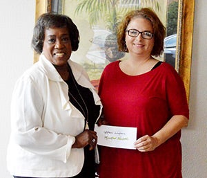 South Central Alabama Mental Health Board member Staci Wilson accepts a contribution from Andalusia Health Services presented by Diaon Cook.